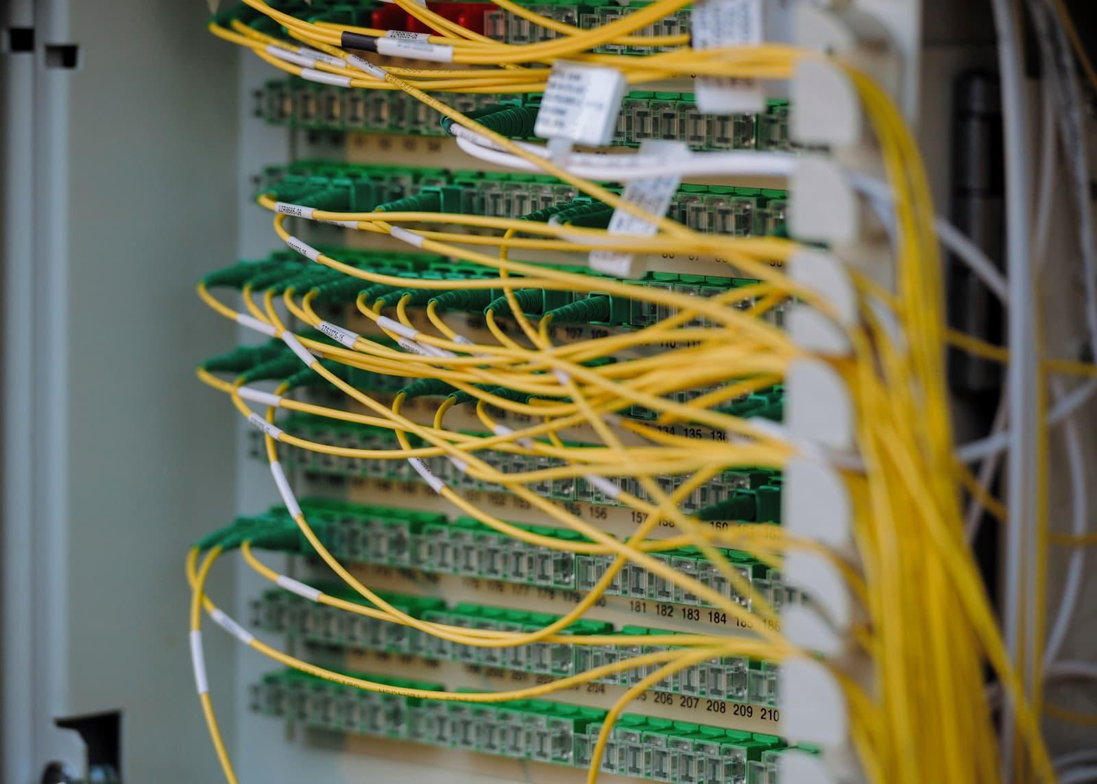A fibre-optic patch panel with labelled single-mode cables terminating in green connectors.
