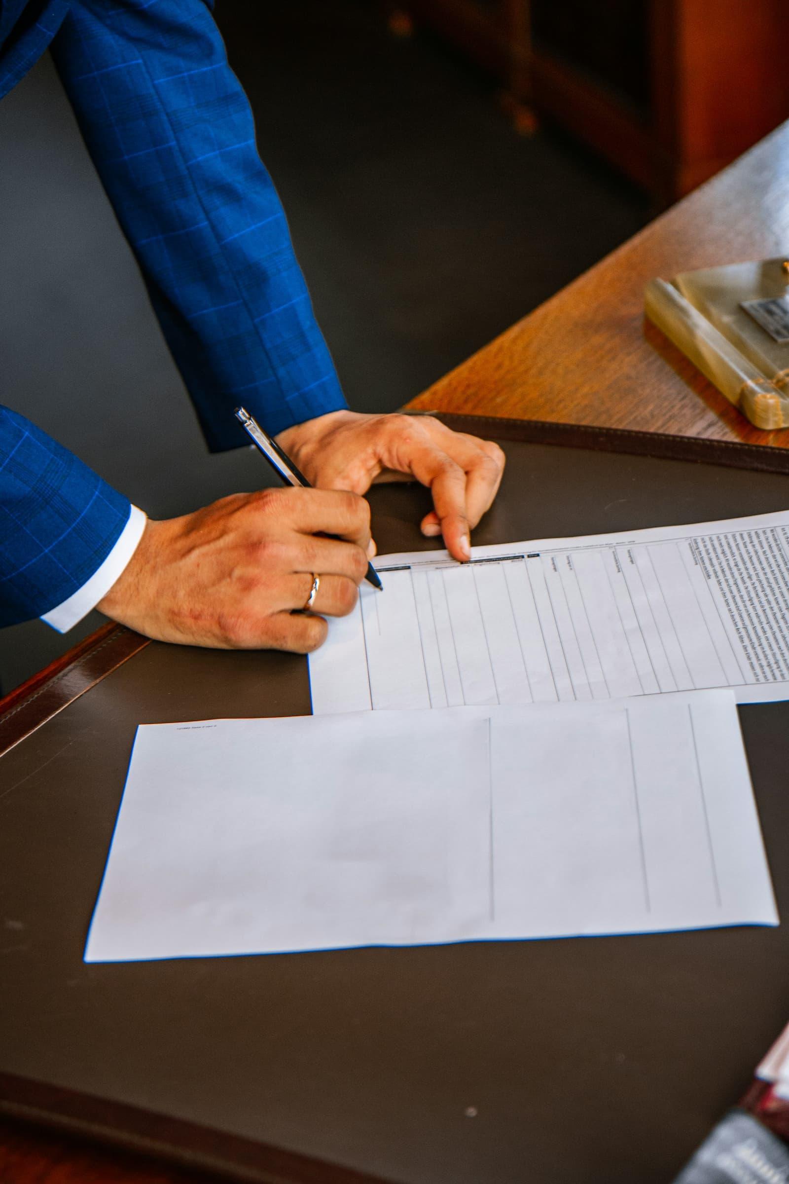 A hand completing a printed form with a pen.