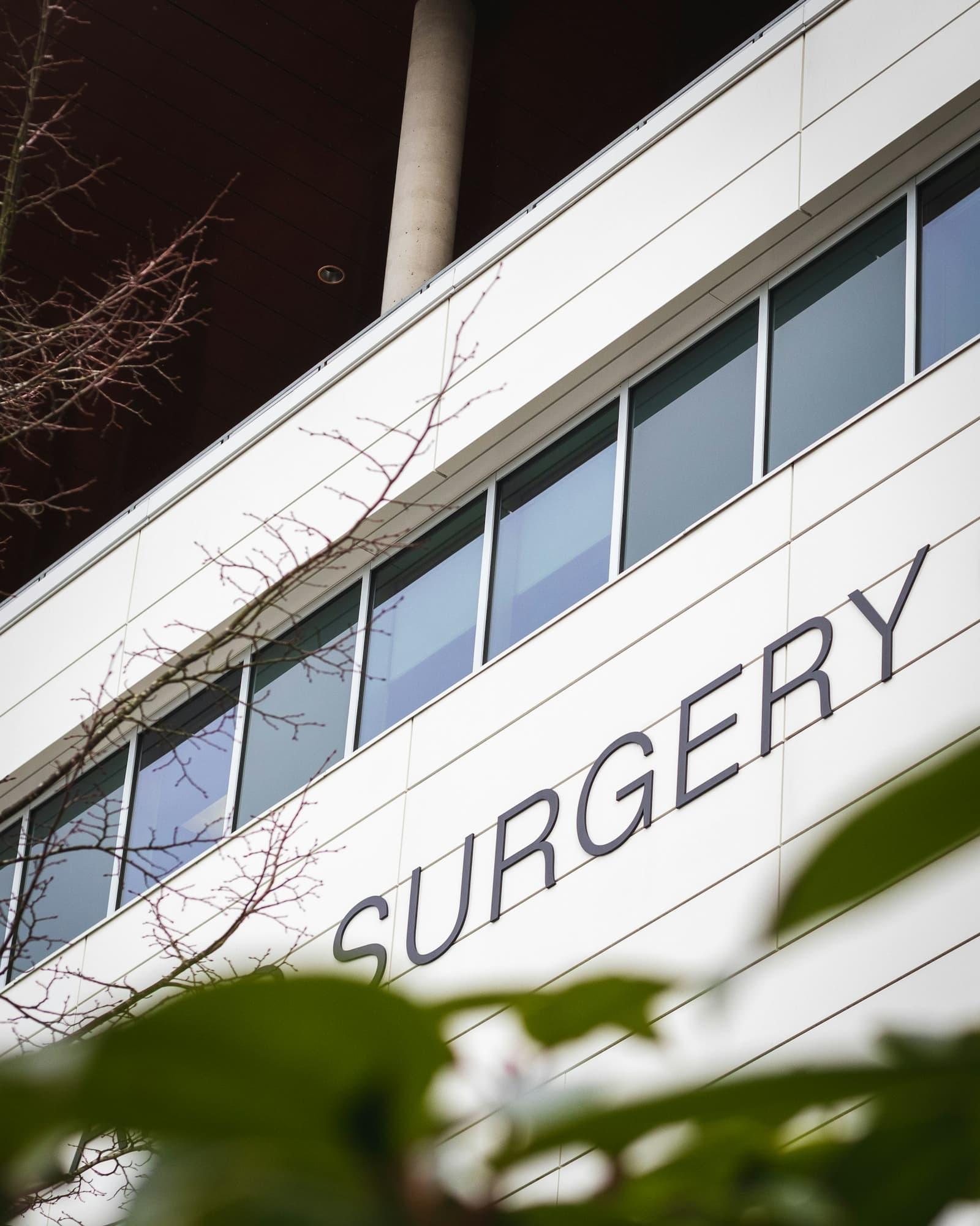 The upper facade of a modern clinical building with the word Surgery lettered across it.