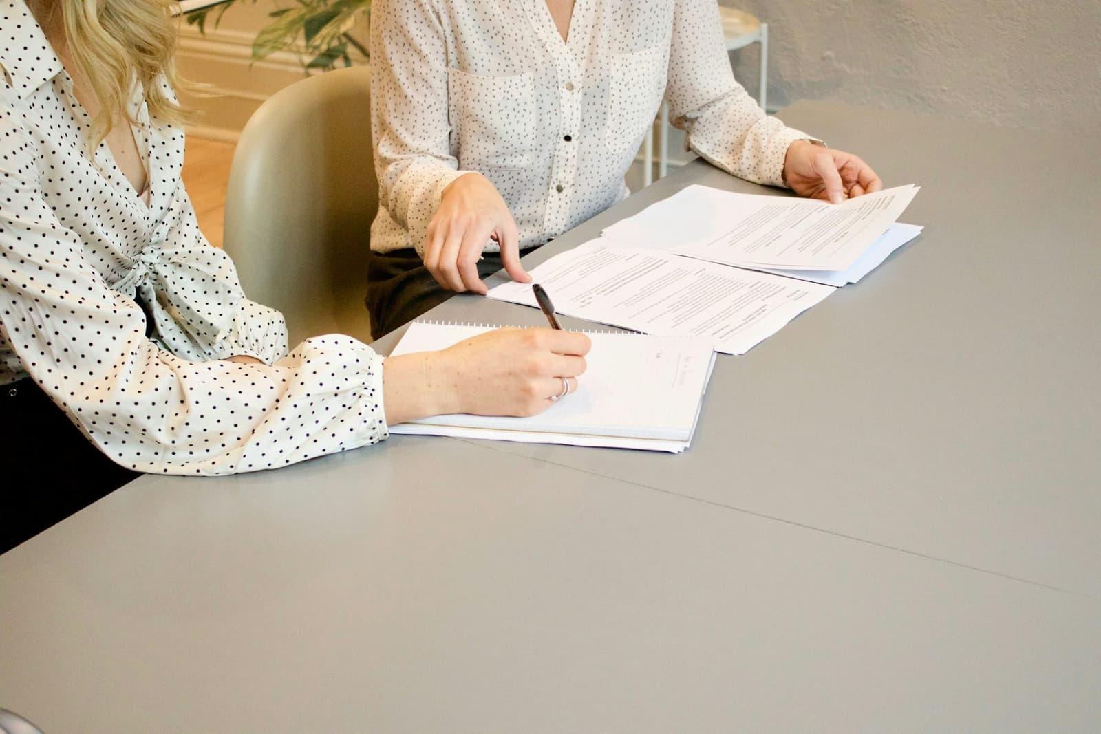 Two people working through a printed contract across a table.