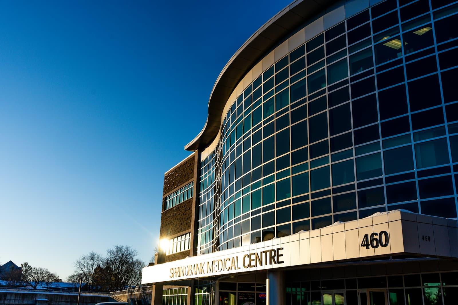 The curved glass facade of a modern medical centre catching low winter sun.
