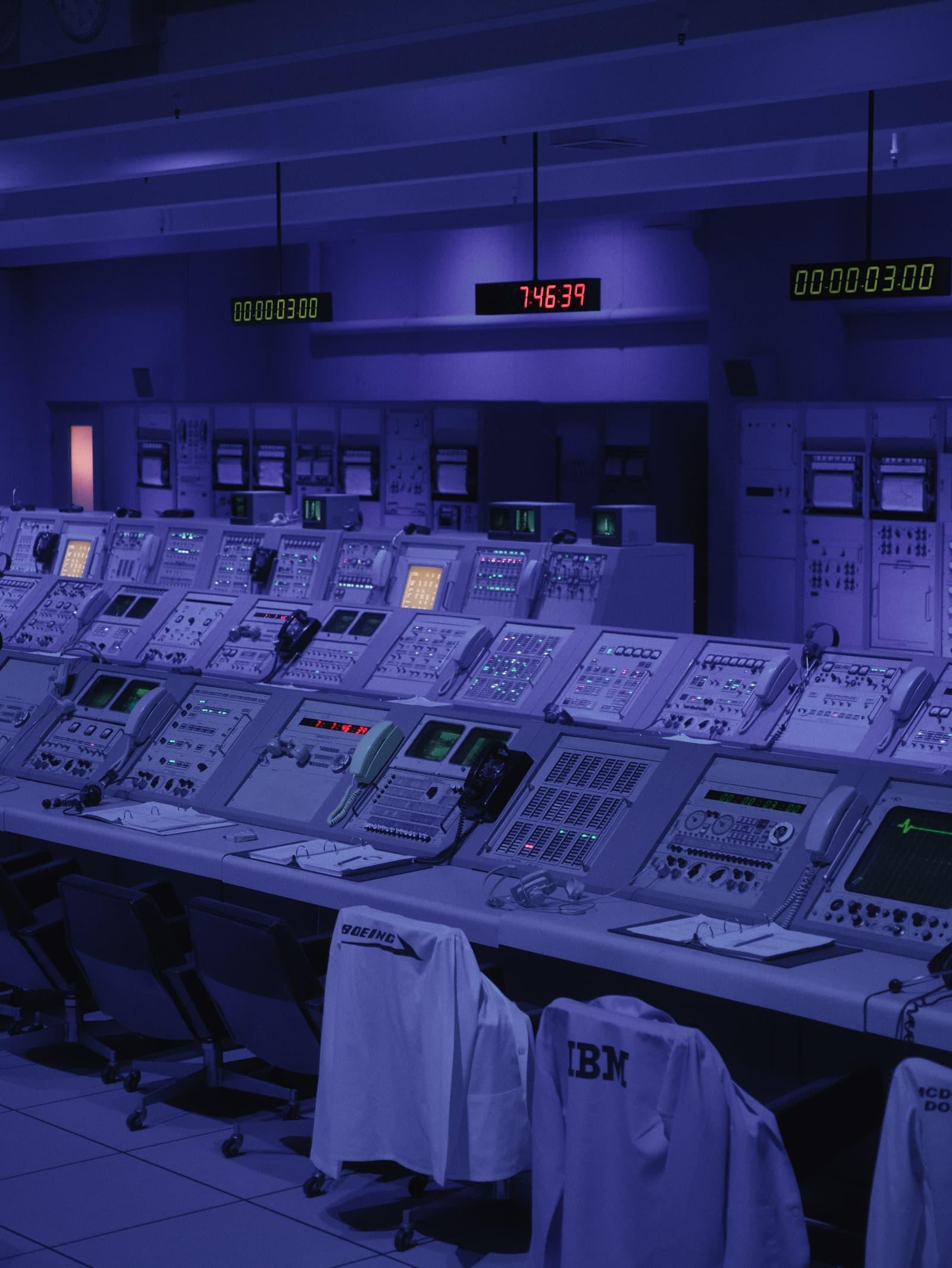 A long console of monitoring stations under low blue light, mission-control style.