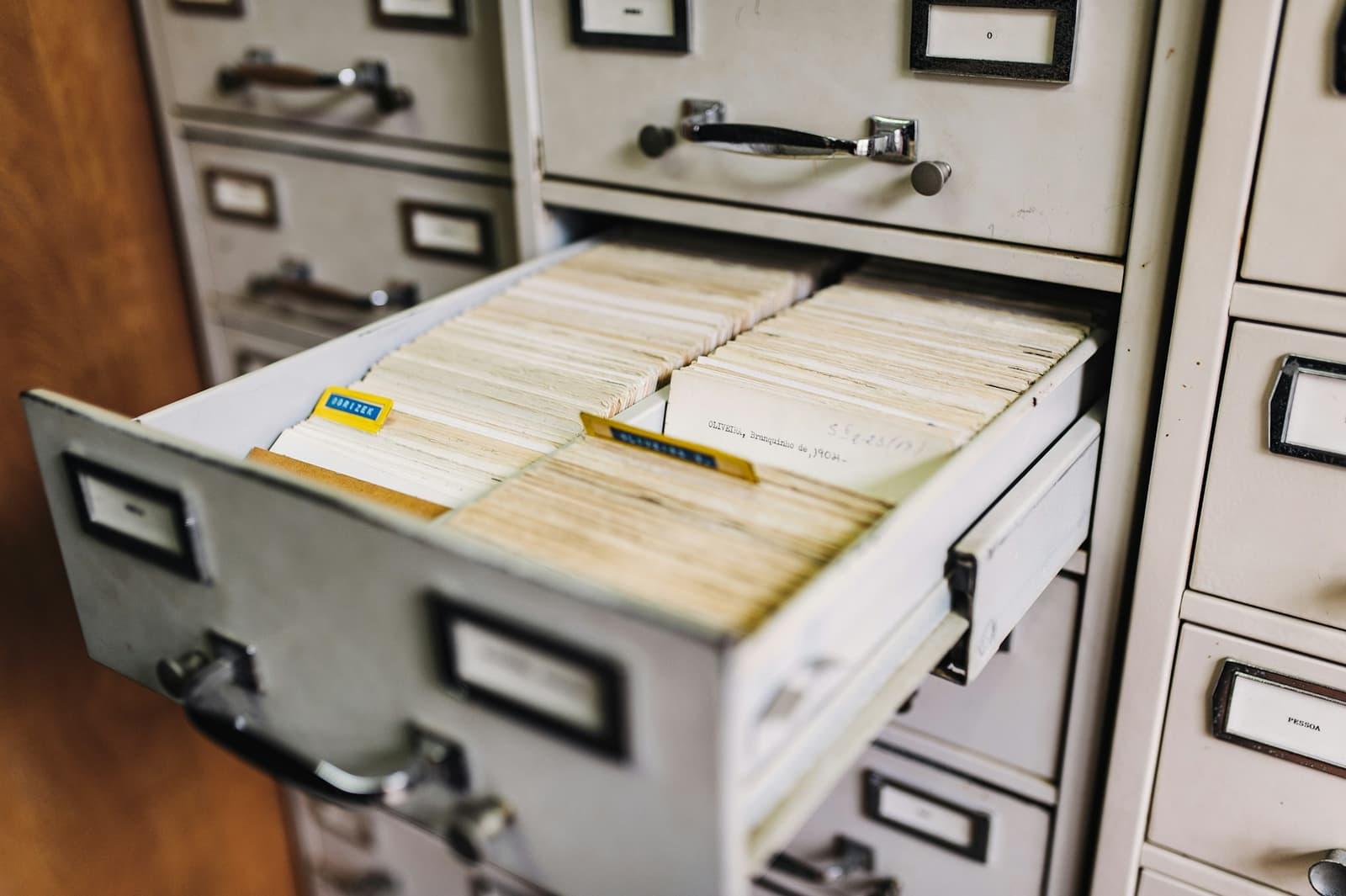 An open drawer of a metal card-index cabinet, packed with hand-filed paper records.