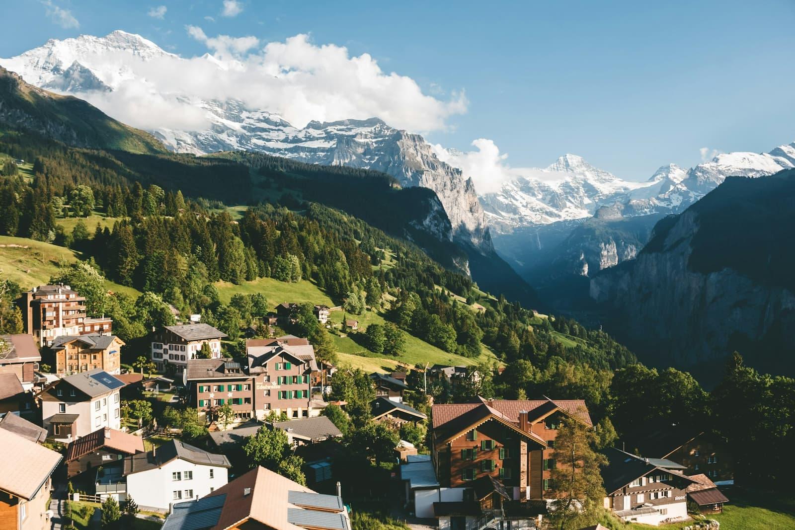 Chalets scattered across a green Swiss mountainside beneath open sky.