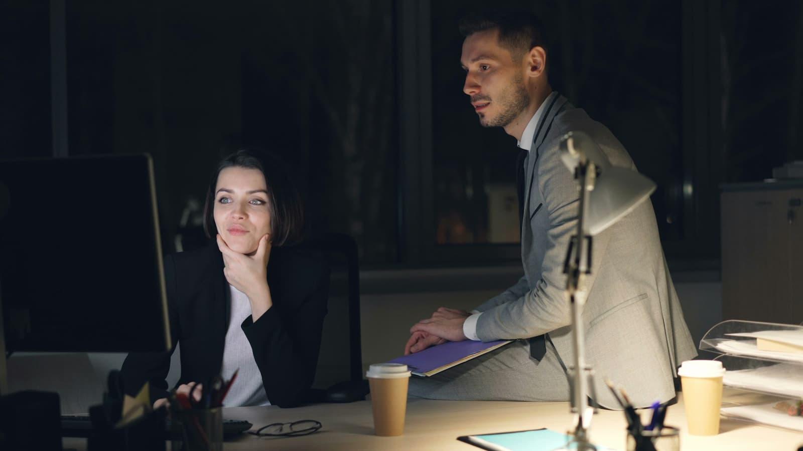Colleagues still at their desks in an office after hours.