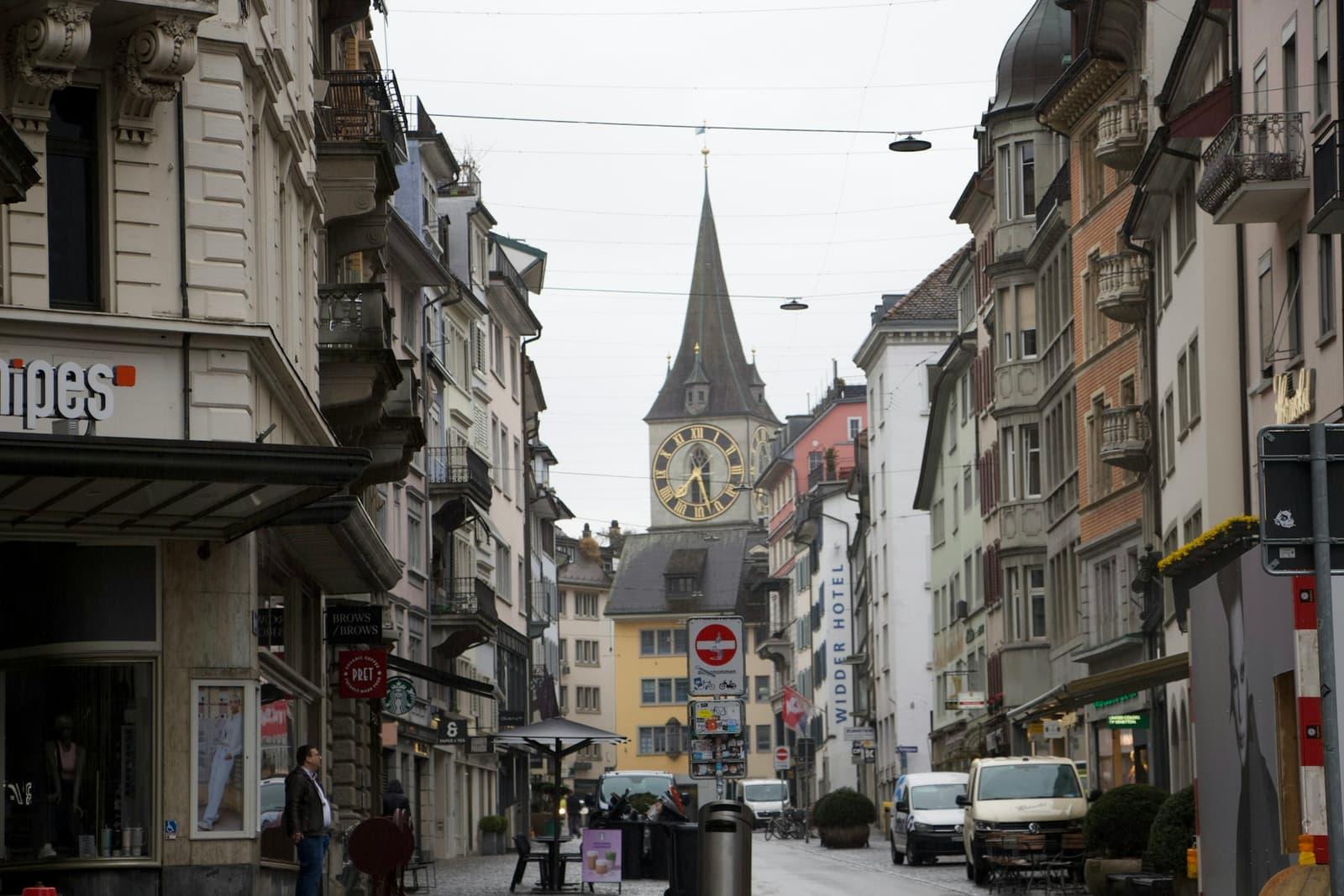 A historic Swiss street leading toward a church clock tower.